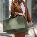 Lieblingstasche Allrounder L travel bag in olive green held by a woman wearing a brown blazer
