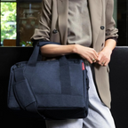 Lieblingstasche Allrounder M navy blue travel bag with shoulder strap carried by a woman in a beige blazer