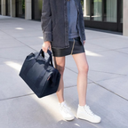 Lieblingstasche Allrounder M navy blue travel bag held by a woman wearing a dark denim jacket and black skirt