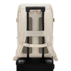 Lieblingstasche Bali Pro cream vegan leather backpack with padded straps and luggage sleeve, attached to a black suitcase.