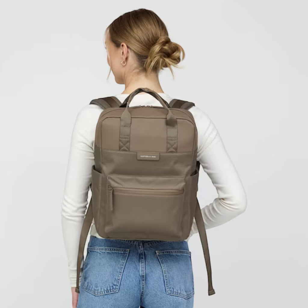 Lieblingstasche Bergen Pro backpack in taupe worn by a woman, featuring padded straps and a laptop compartment.