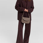 Model wearing a dark burgundy suit carrying a taupe suede Big Sister Suede handbag by Lieblingstasche