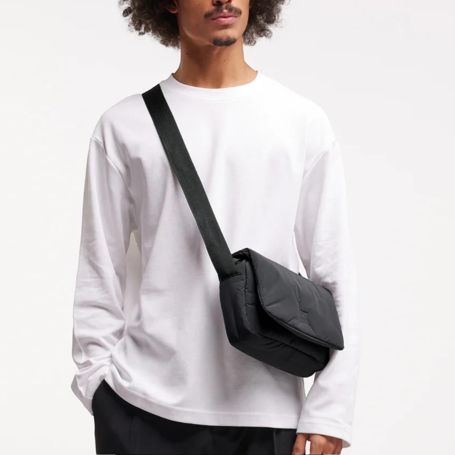Lieblingstasche Cloud Crossbody Bag in black, made from water-resistant RE:NYNET material, worn by a male model.