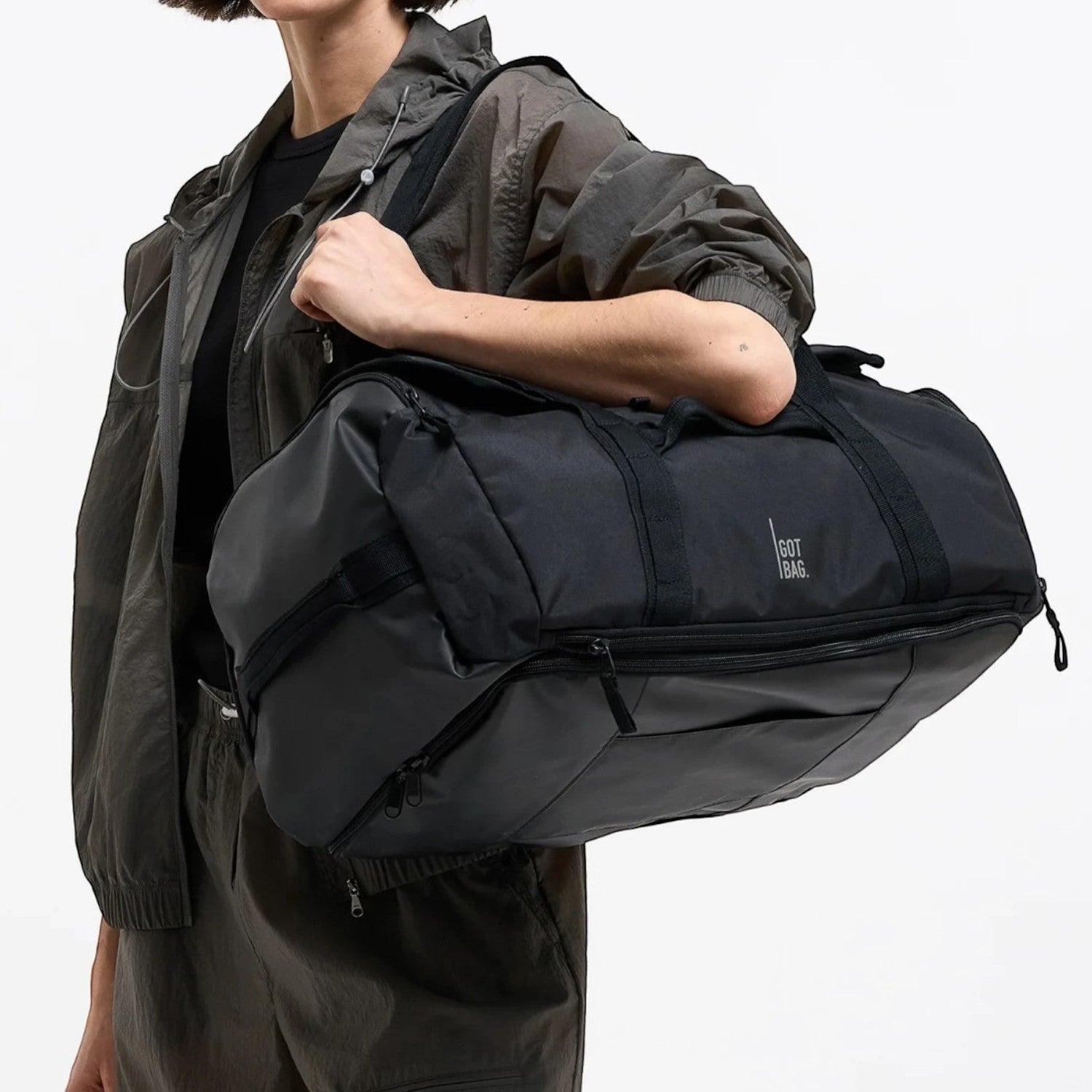 Lieblingstasche black duffle pack with multiple zippered compartments and handles, worn by a woman.