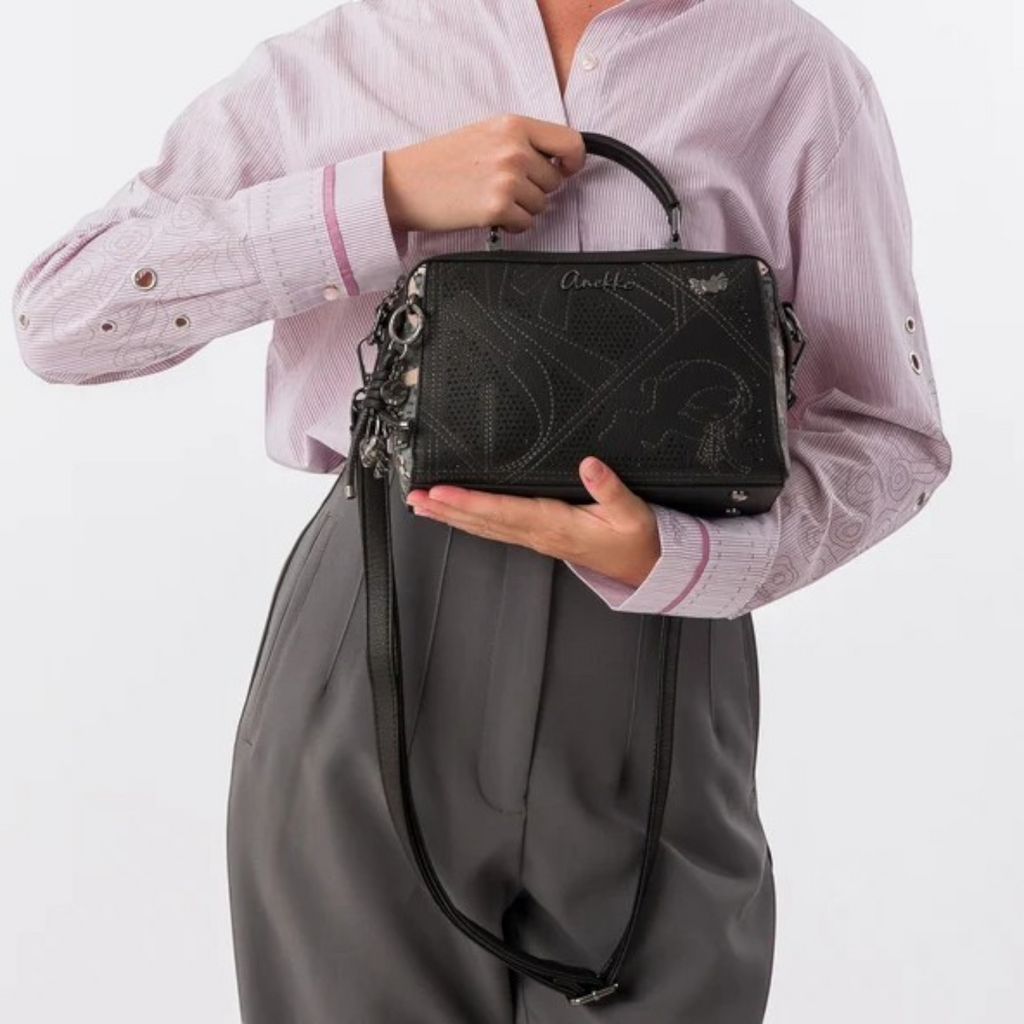 Lieblingstasche black cross-body bag with perforated geometric patterns and a top handle held by a woman