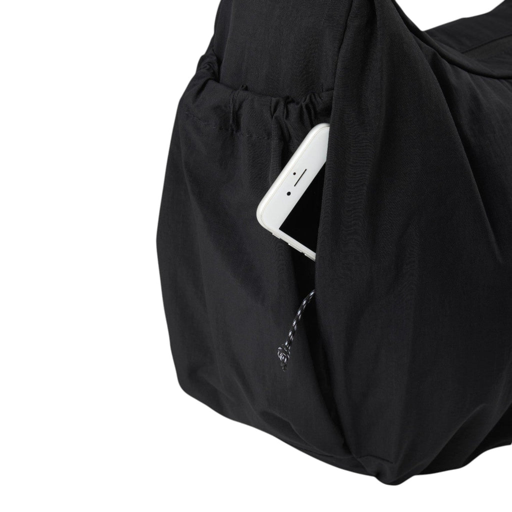 Lieblingstasche black slouchy bag featuring a convenient side pocket with a white smartphone tucked inside