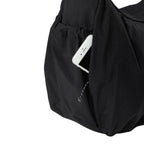 Lieblingstasche black slouchy bag featuring a convenient side pocket with a white smartphone tucked inside