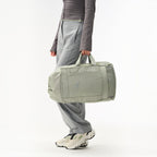 Lieblingstasche Blok Medium sage green travel bag with side pockets and top handles held by a person
