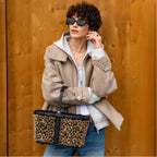 Lieblingstasche Carrybag XS with a leopard print pattern, black frame, and handle held by a woman in a beige jacket.