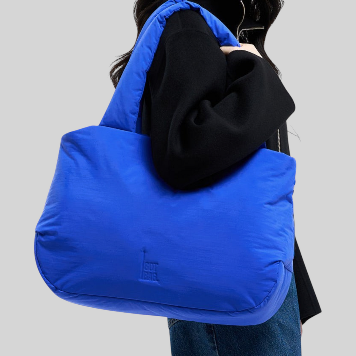 Lieblingstasche Cloud Horizon tote bag in bright blue, worn over the shoulder by a model in a black jacket.