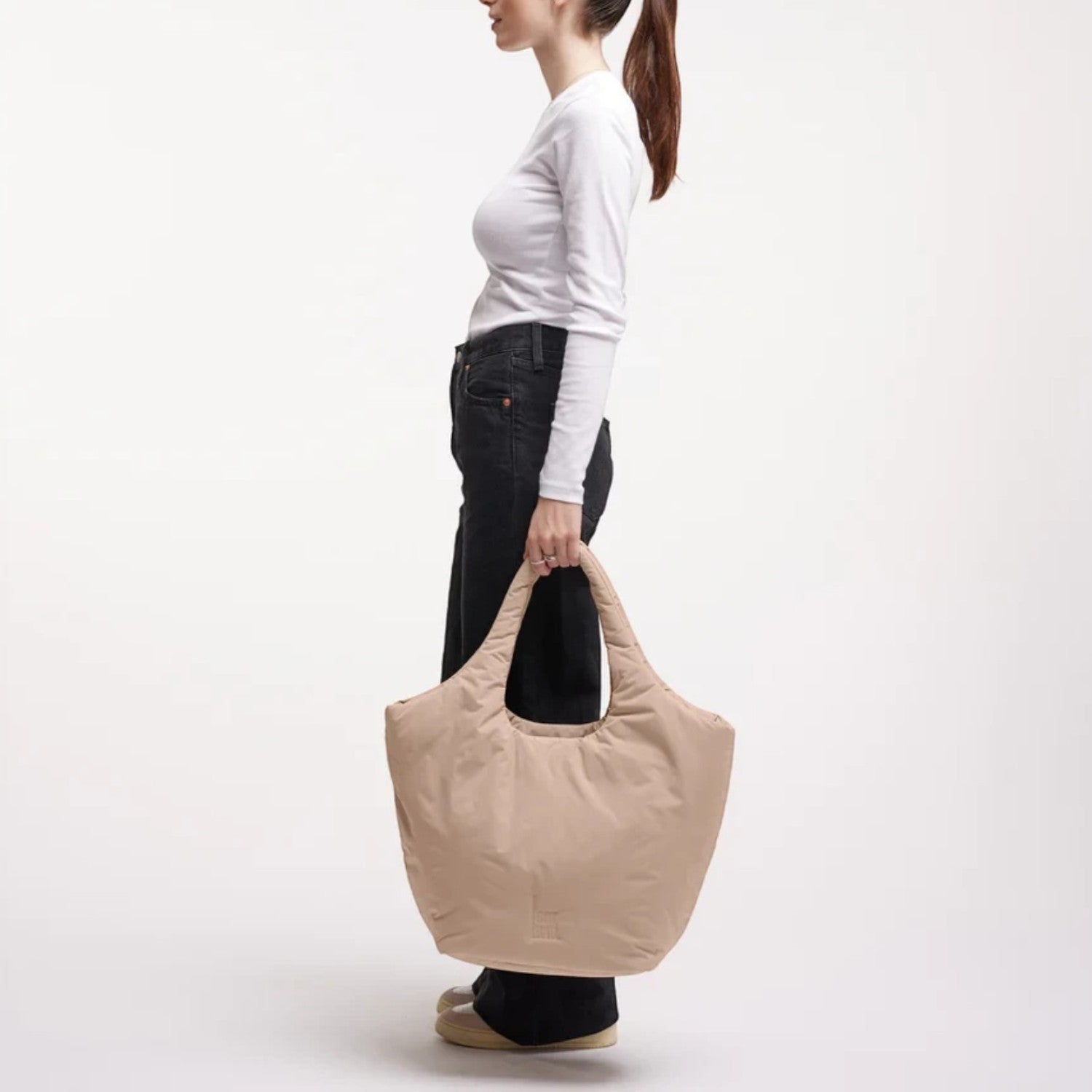 Lieblingstasche Cloud Tote Bag in beige, made from water-resistant RE:NYNET material, held by a woman in profile.