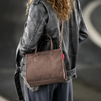 Lieblingstasche Daily Shopper XS in brown teddy fleece worn as a crossbody bag by a woman in a leather jacket