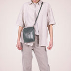 Lieblingstasche dark green leather fold-over clutch handbag with silver clasp and adjustable strap.