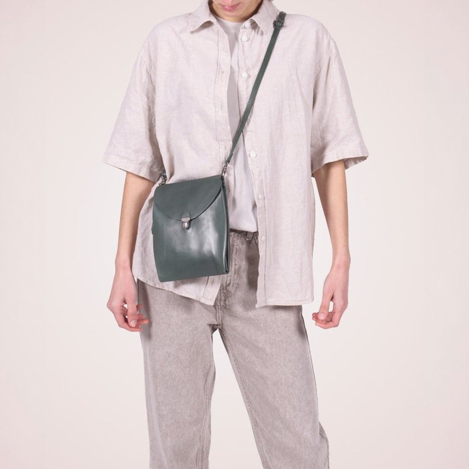 Lieblingstasche dark green leather fold-over clutch handbag with silver clasp and adjustable strap.