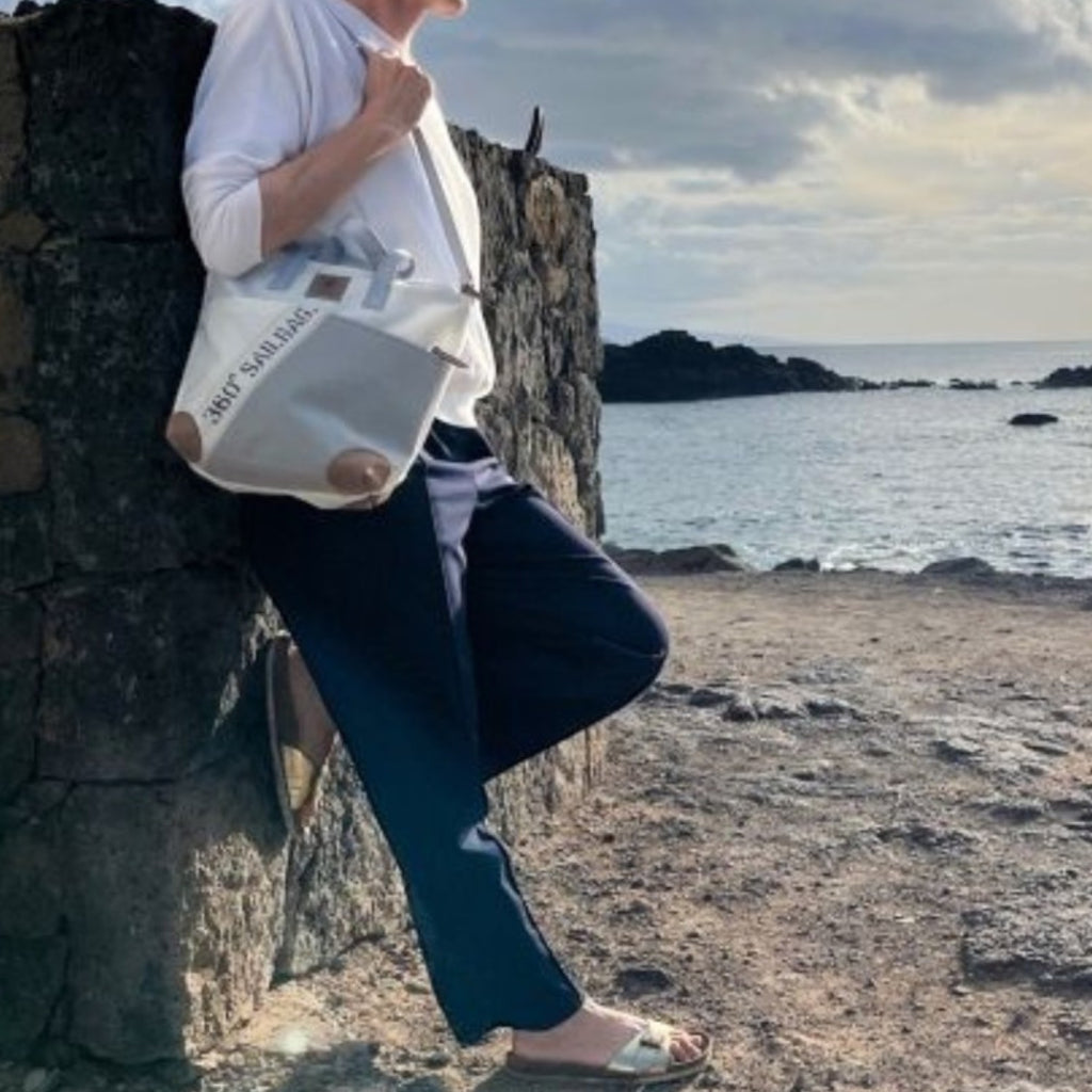 Lieblingstasche Deern Mini handbag made from recycled sailcloth with maritime design, worn by a woman at the coast.