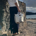 Lieblingstasche Deern Mini handbag made from recycled white sailcloth held by a woman by the sea.