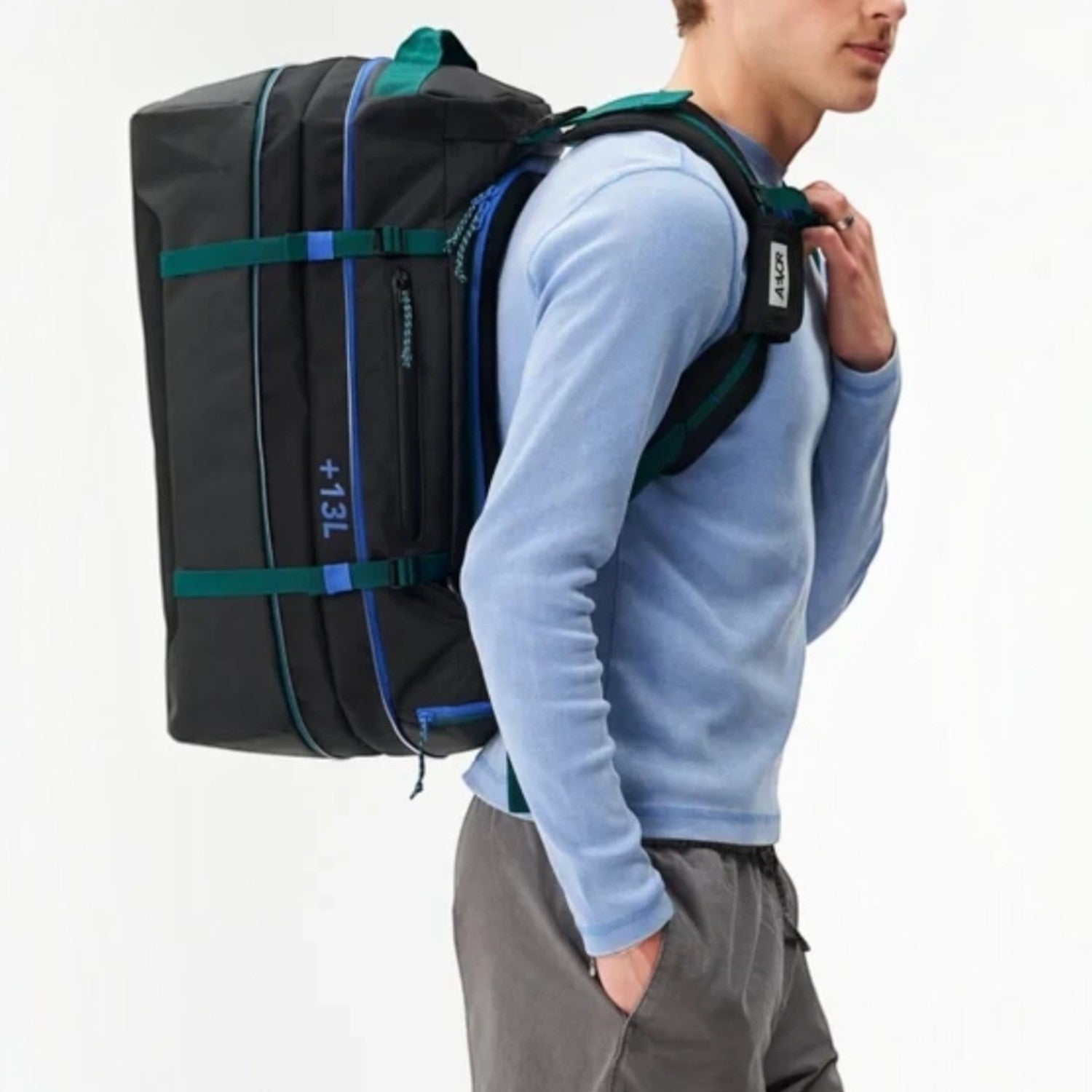Lieblingstasche Duffel Pack in black with green straps and blue accents worn as a backpack by a male model