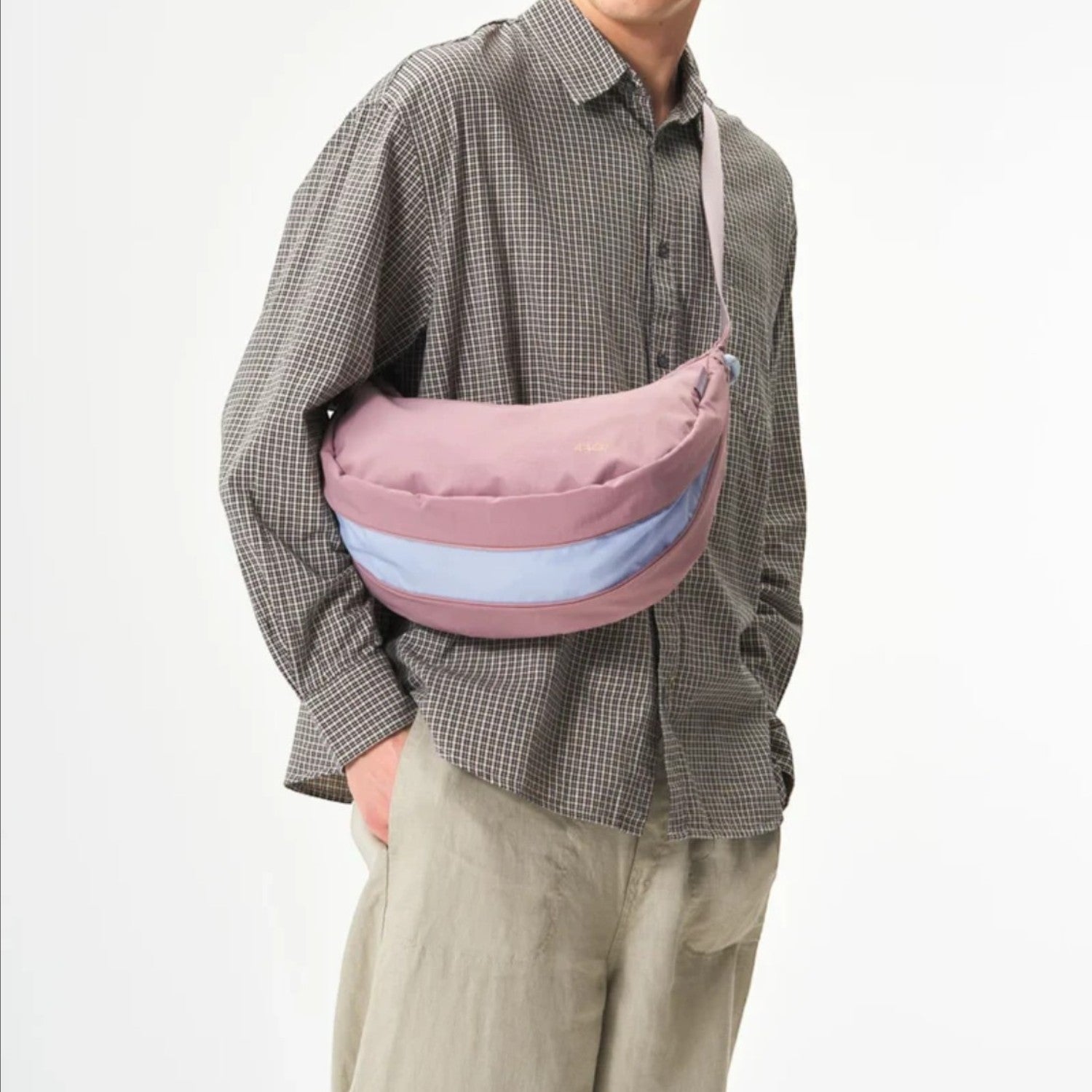 Lieblingstasche sling bag in dusty rose and light blue worn crossbody by a man in a plaid shirt and beige cap