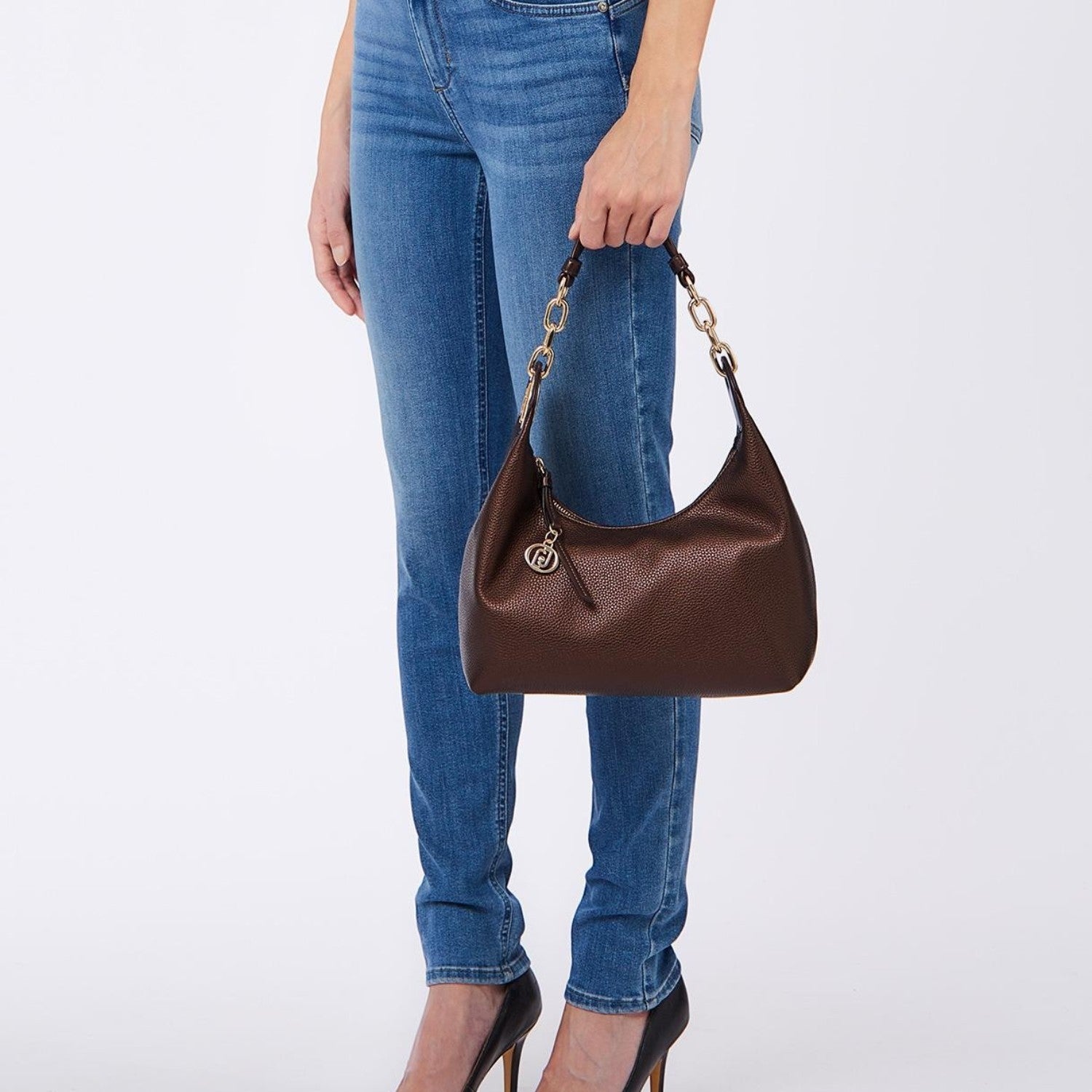 Lieblingstasche ECS Hobo S dark brown shoulder bag with gold chain strap detail held by a woman in jeans