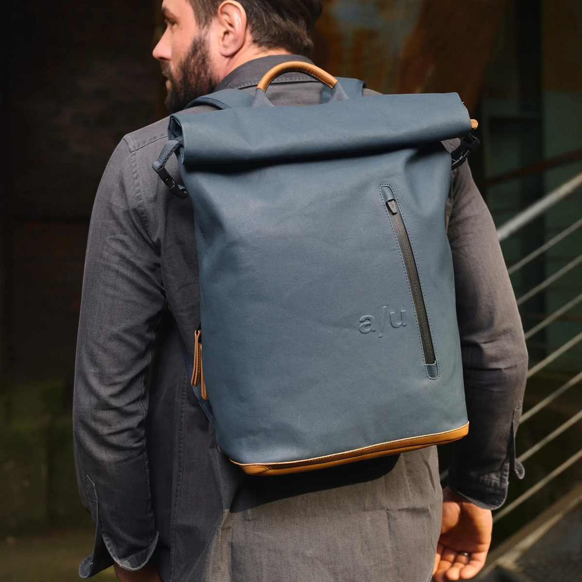 Lieblingstasche a/u by aunts & uncles Fukui blue rolltop backpack with leather details worn by a man