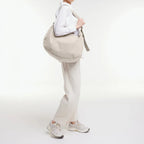 Lieblingstasche GOT BAG curved shoulder bag in beige worn by a model in a white outfit against a studio background