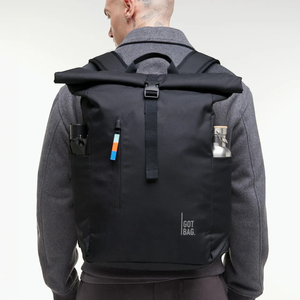 Lieblingstasche GOT BAG Rolltop Easy backpack in black, worn on a man's back with side pockets for water bottles.