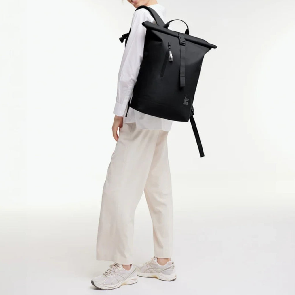 Lieblingstasche GOT BAG Rolltop Lite 2.0 black backpack worn by a woman in a white shirt and beige trousers