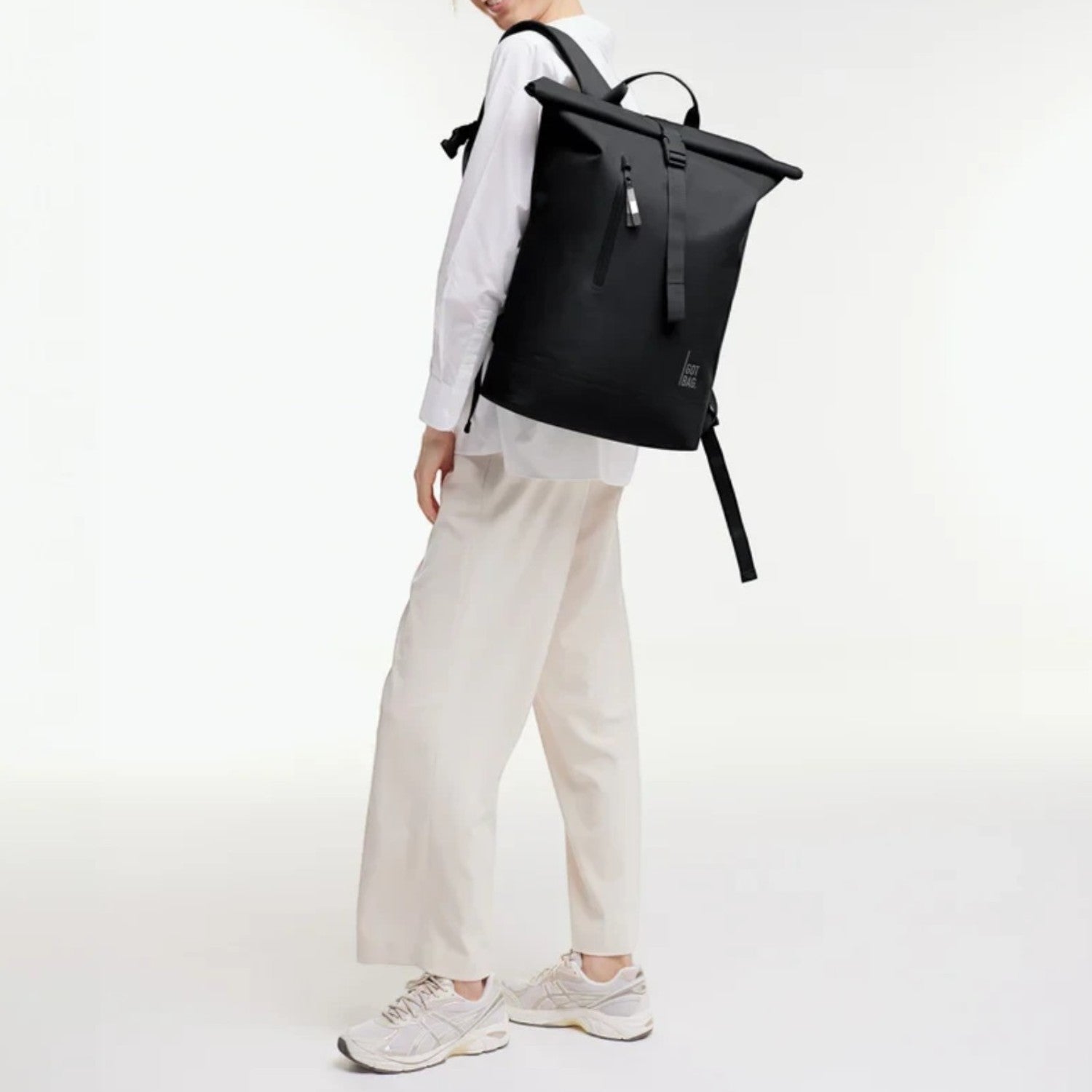 Lieblingstasche GOT BAG Rolltop Lite 2.0 black backpack worn by a woman in a white shirt and beige trousers