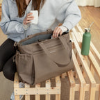 Lieblingstasche Hellvi Pro Large taupe tote bag with side pockets and top handles held by a person