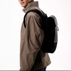 Lieblingstasche Kapten & Son Fyn minimalist black backpack worn by a man in a brown jacket against a white background