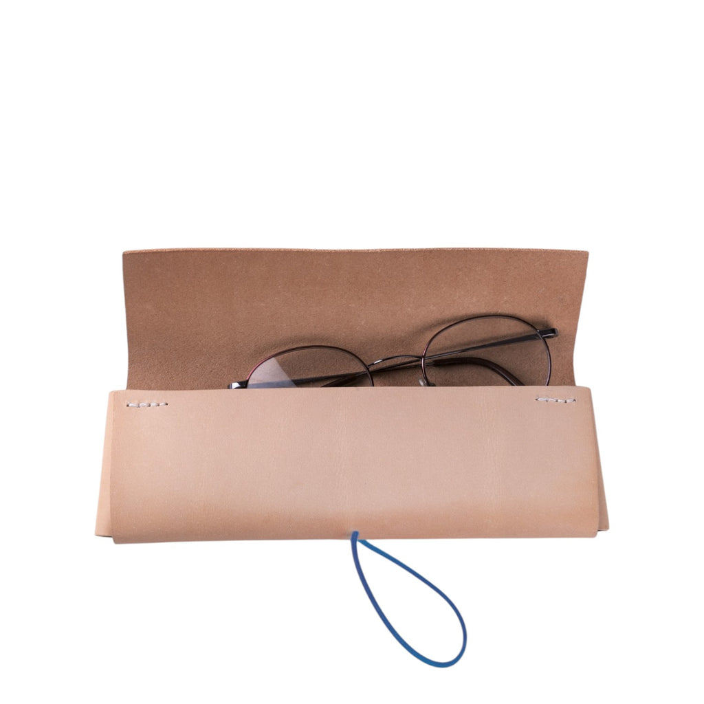 Lieblingstasche Keeper Etui made of natural beige leather with a blue elastic closure holding eyeglasses