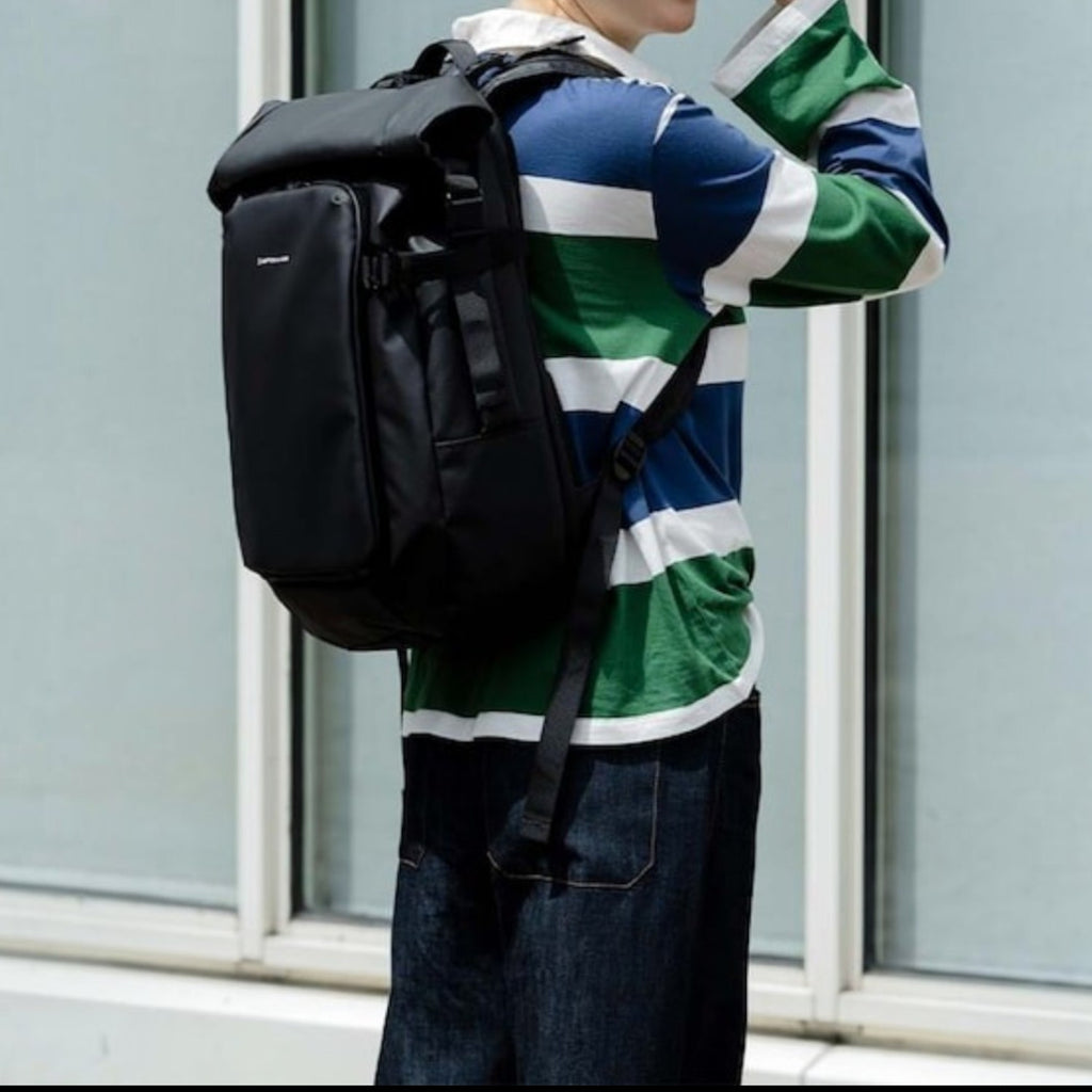 Lieblingstasche Lisbon Pro black travel backpack worn by a woman in a striped shirt outdoors