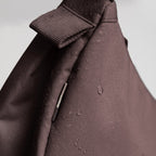 Lieblingstasche Moon Bag Small in dark brown water-repellent fabric with visible water droplets on the surface
