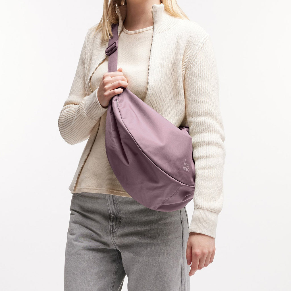 Lieblingstasche Large Moon Bag in dusty rose, made of nylon, worn crossbody by a woman.