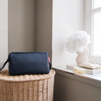 Lieblingstasche Travelcosmetic navy blue toiletry bag sitting on a wicker basket near a bright window
