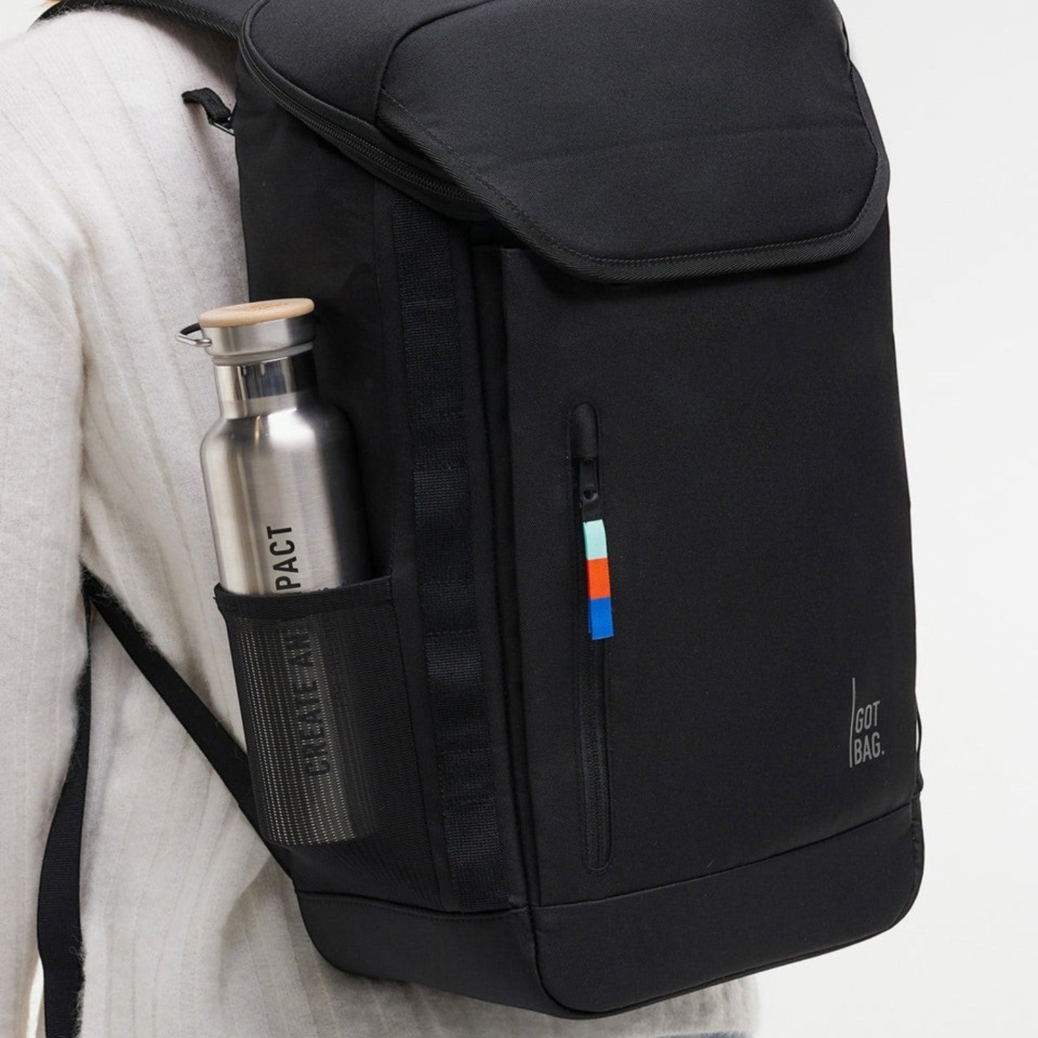 Lieblingstasche Pro Pack black backpack with side mesh pocket holding a metal water bottle, worn on a person's back.