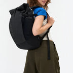 Lieblingstasche Roll Pack 2.0 black backpack with rolltop closure worn by a woman against a white background