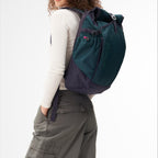 Lieblingstasche Roll Pack 2.0 in dark green and navy blue worn by a woman against a white background