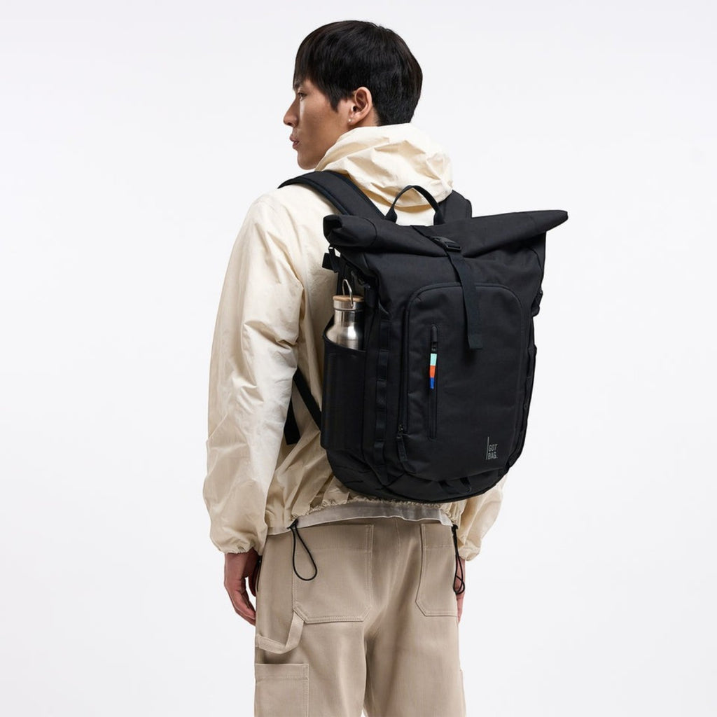 Lieblingstasche Rolltop Adventure black backpack with water bottle in side pocket and colorful stripe detail.
