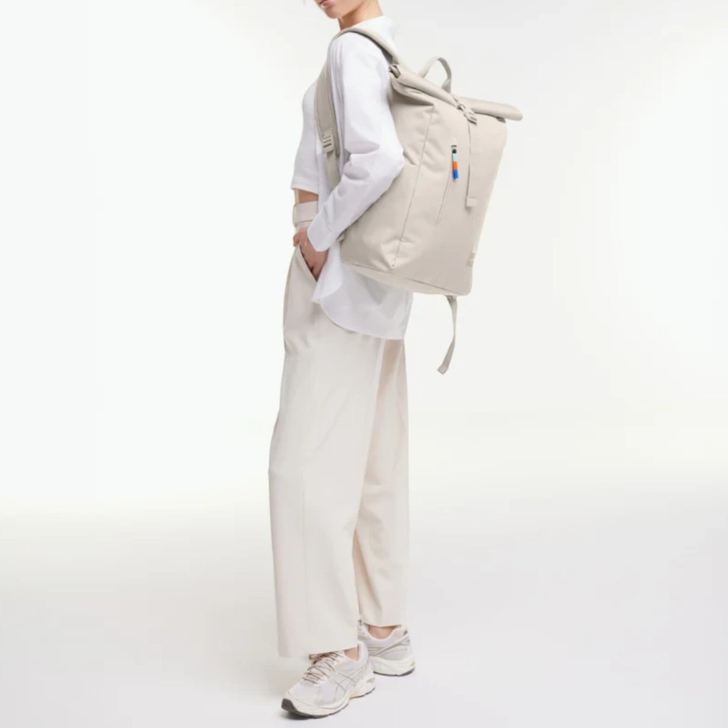Lieblingstasche Rolltop Easy backpack in beige worn by a woman in a white outfit against a plain studio background.