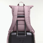 Lieblingstasche Rolltop Easy lilac backpack with padded straps, attached to a black suitcase.