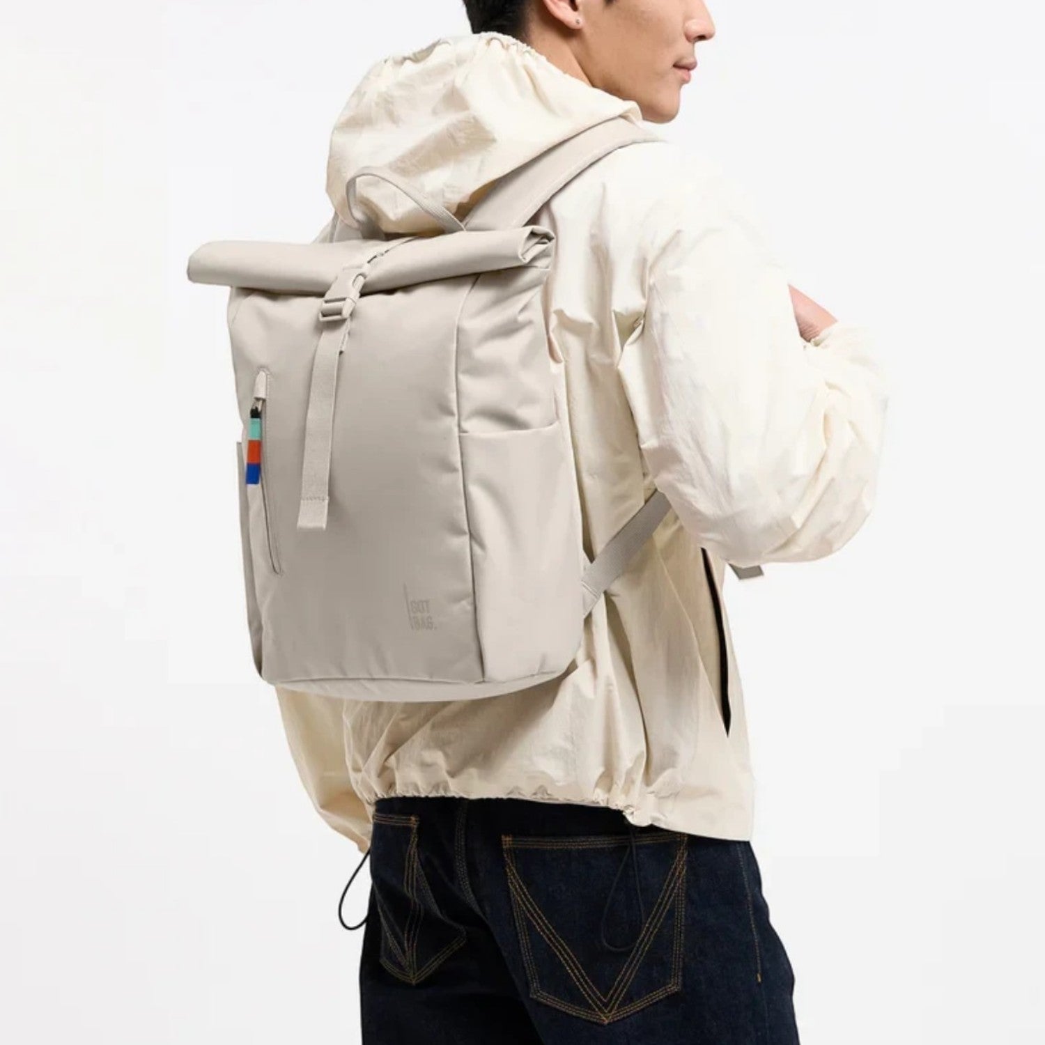 Lieblingstasche Rolltop Easy Small backpack in beige worn by a man, featuring a rolltop closure and side pockets.