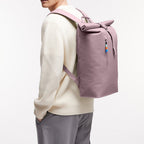 Lieblingstasche Rolltop Lite 2.0 lilac backpack with zip pocket and colorful zipper pull, worn by a person in a cream sweater.