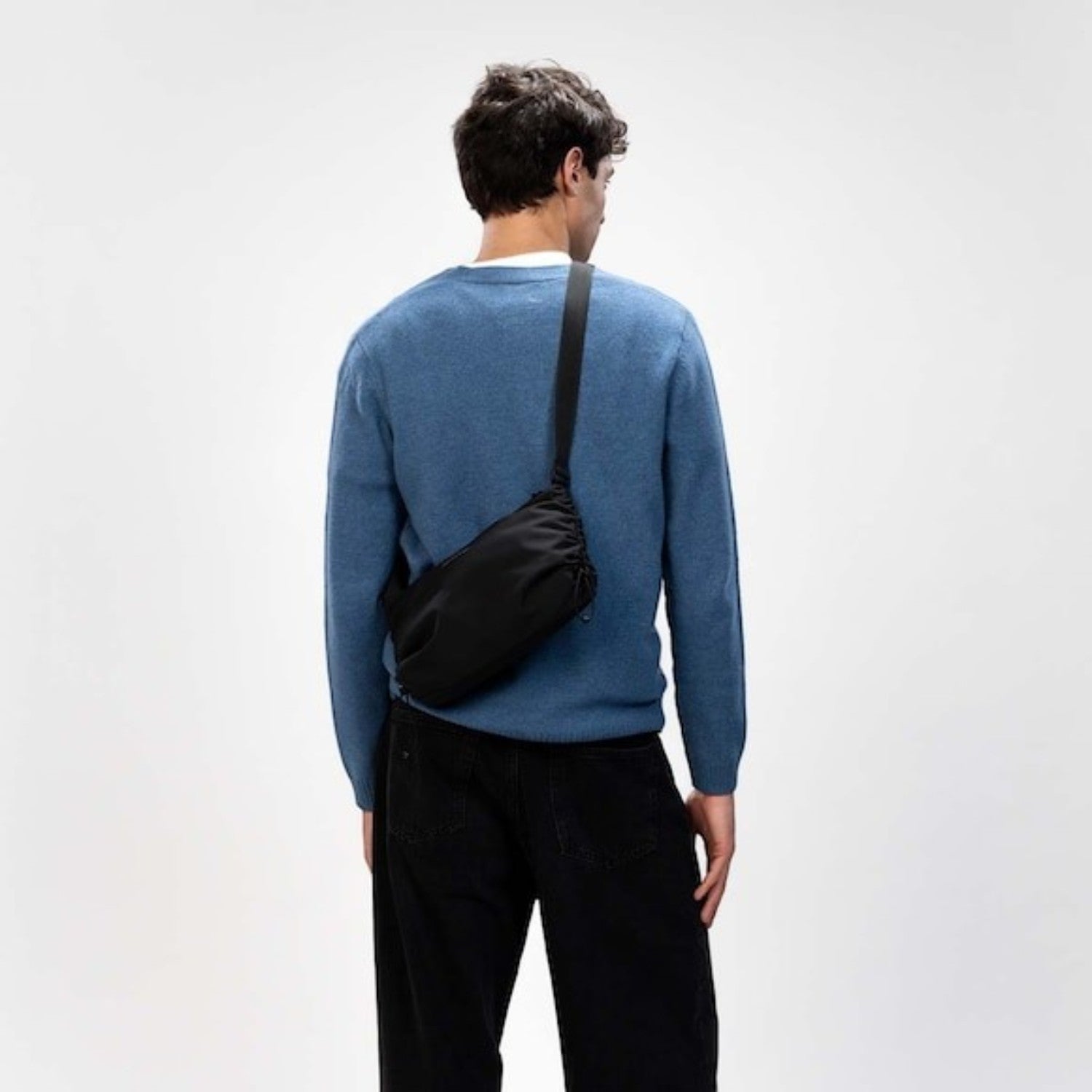 Man wearing a black Kapten & Son Skara Small crossbody bag from Lieblingstasche with a blue sweater and black jeans.
