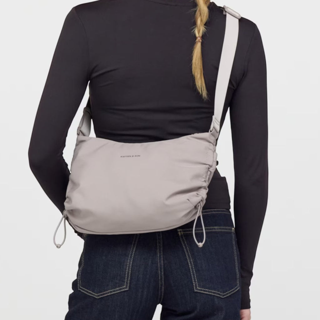 Lieblingstasche Skara Small grey crossbody bag worn by a woman in a black long-sleeve top and dark blue jeans