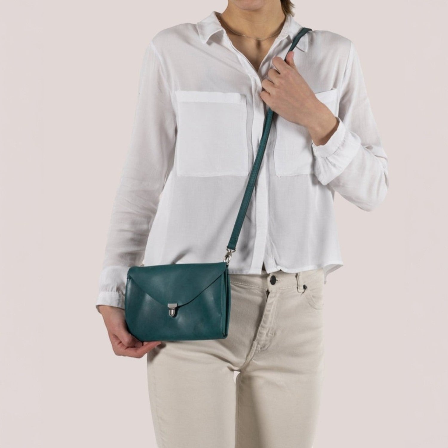 Lieblingstasche Fold Handbag Clutch M in teal leather with a silver clasp and adjustable strap.