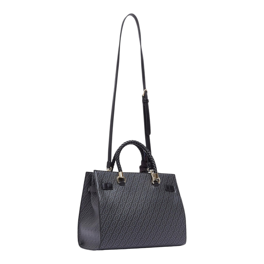 Lieblingstasche Tote M in black with a repeating logo pattern, braided top handles, and an adjustable shoulder strap.