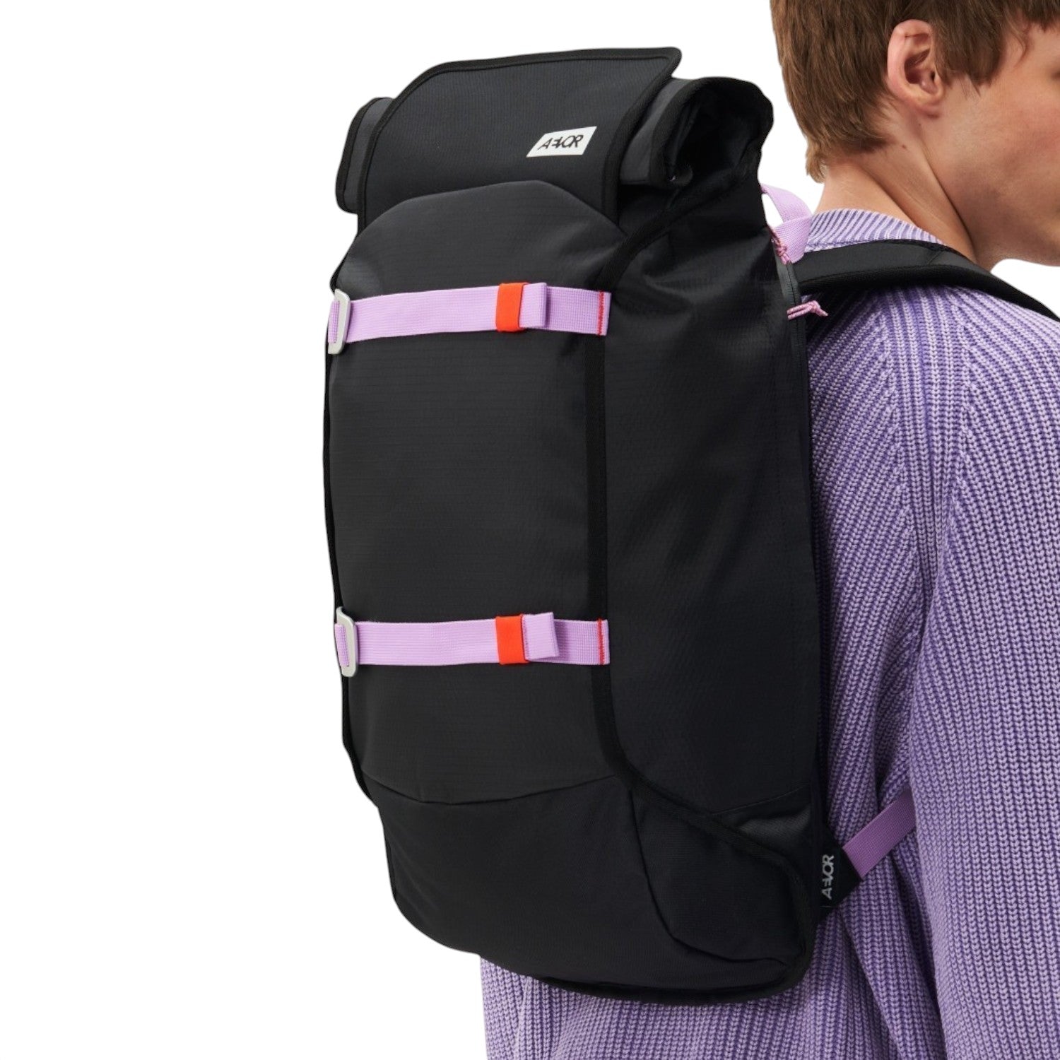 Lieblingstasche Trip Pack black backpack with purple straps worn by a man in a lavender sweater